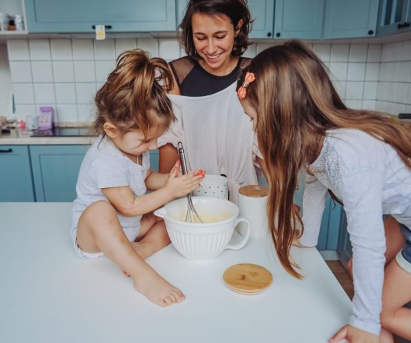 Mom and two daughters cook together in the kitchen